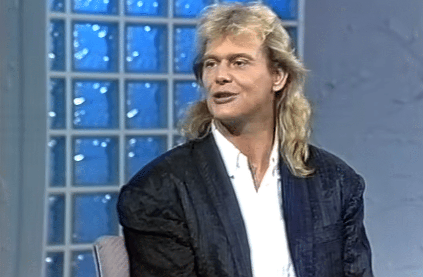 john farnham illness Some voices cut you off in the middle of a conversation. One of those belonged to John Farnham. Something changed in the room when he opened up on stage; it's the kind of change that's hard to explain logically but obvious when it occurs. For more than 50 years, that presence and voice shaped Australian popular music. This is why it's so difficult to accept the news from late September. The man who used to hold stadiums captive now needs constant oxygen support, uses a wheelchair to move around, and gets round-the-clock nursing care at home. In a statement issued late on Friday nite, his family—Jill, his wife of more than 50 years, and their sons Robert and James—made the announcement. It happened in an odd order. Rob, John's son, had made an appearance on A Current Affair earlier that day, assuring viewers that although John wasn't well enough to attend a tribute concert at Melbourne's Rod Laver Arena, he was "so good... he's back to his old self." The family's written statement, which was released hours later, painted a very different picture. Rob was probably attempting to protect his father and provide some small dignity in a circumstance that doesn't permit much of it, which is what makes that scene uncomfortable rather than malice or intentional deceit. However, there was a noticeable discrepancy between what the family published in writing and what he said on television. The statement stated that "John's health has deteriorated in recent months" and that the number of inquiries regarding whether the 77-year-old Farnham would perform at the concert in his honor forced them to make the announcement public. He won't. He was unable to. All of this began in August 2022, when Farnham underwent more than eleven hours of surgery after receiving a diagnosis of oral cancer. A type of head and neck cancer that, when detected and treated, has a respectable survivorship rate but rarely leaves people unharmed was removed from the oral cavity during the procedure. Changes in speech and swallowing, breathing tubes, and jaw reconstruction are not transient inconveniences. They become lifelong realities for certain patients. The repercussions were always going to be dire for a man whose voice was the foundation of his entire career. When Australia learned that he was cancer-free in 2023, there was a general exhale. However, being declared cancer-free and regaining full health are two different things. Earlier this year, Farnham himself admitted that he would never sing again. Too much had changed in the surgeries. It's the kind of thing that is said quietly, almost casually, and it should have gotten more attention than it most likely did in the news cycle. Nobody fully anticipated the weight of the Rod Laver Arena tribute. In the shadow of his family's sobering public statement, an all-star event intended to honor a career—and a remarkable one, spanning more than 50 years—now took place. Observing all of this from a distance gives the impression that the concert was subtly fulfilling a function other than celebration. No one would describe it quite as a send-off, but it was more akin to that. Released in 1986, John Farnham's most well-known song became a cultural icon that transcends individual careers. Rallies, athletic events, and times when people want to feel something greater than themselves are all places where it is played. It is quite ironic that the man who made that recording, who inspired a generation to speak up and raise their voices, is no longer able to sing. When you allow it, it sits with you. Following the family's statement, there was an instantaneous and sincere outpouring of support. The Yellow Wiggle, Greg Page, publicly declared his love. Thousands of comments were left by fans, the kind of spontaneous, unplanned emotional reaction that reveals something genuine about the bond Australian audiences had formed with this specific singer over the course of four decades. john farnham illness